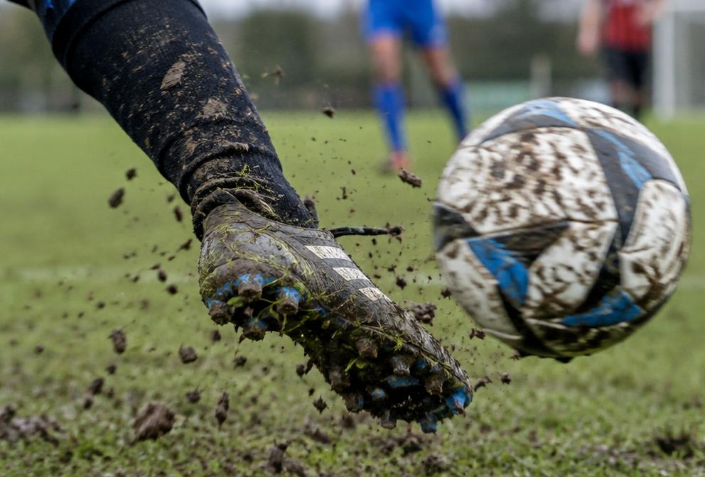 Mud-splattered boot striking a ball
